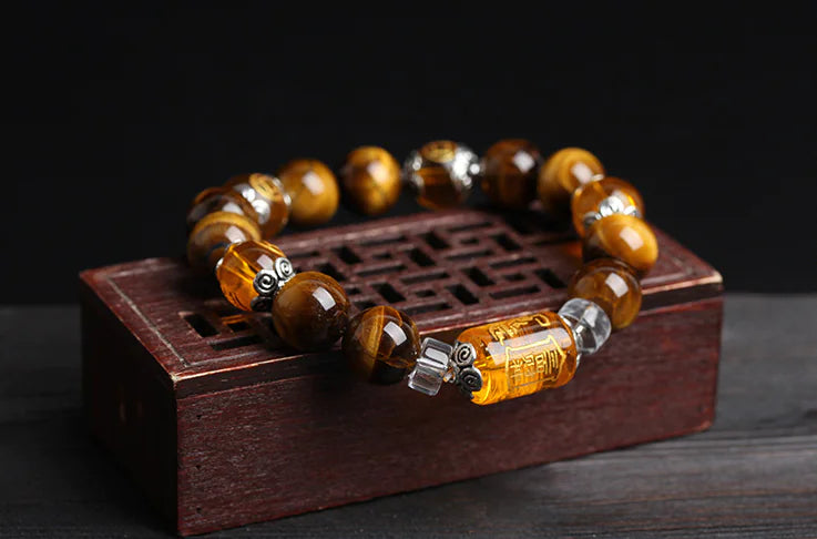 Bracelet with tiger eye beads on a wooden stand against a dark background